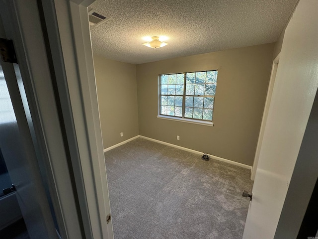 carpeted empty room featuring a textured ceiling