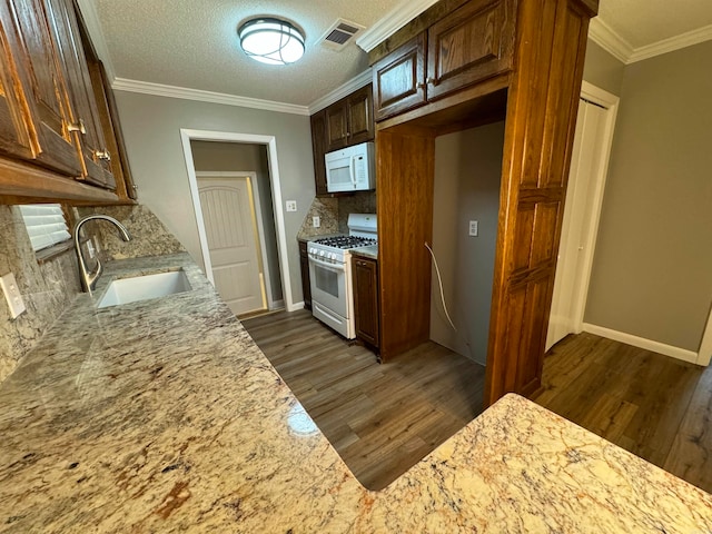 kitchen featuring white appliances, light stone counters, tasteful backsplash, and sink