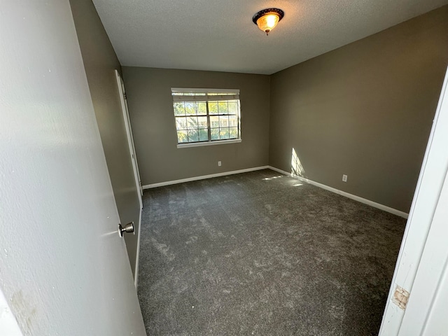 empty room featuring a textured ceiling and dark colored carpet