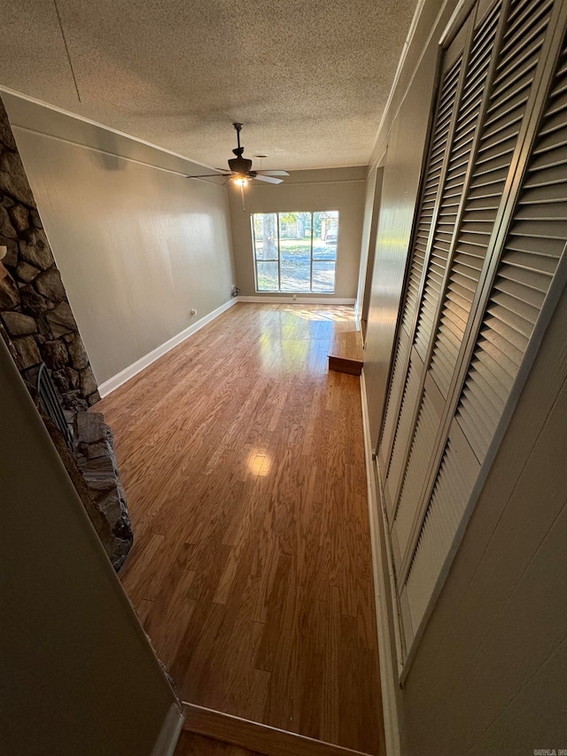 unfurnished living room featuring ceiling fan, a textured ceiling, and hardwood / wood-style floors