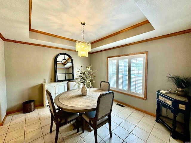 dining space with a textured ceiling, a chandelier, a tray ceiling, light tile patterned flooring, and crown molding