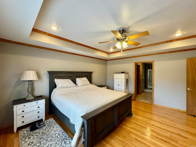 bedroom featuring light hardwood / wood-style floors, crown molding, a tray ceiling, and ceiling fan