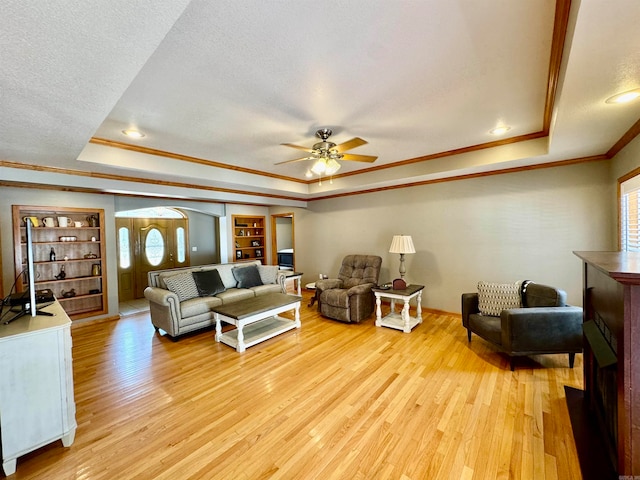 living room featuring light hardwood / wood-style flooring, a tray ceiling, and ceiling fan