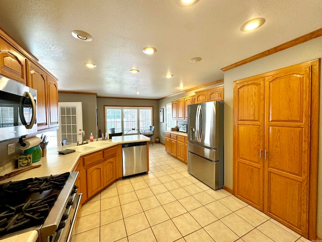 kitchen featuring stainless steel appliances, ornamental molding, light tile patterned floors, and a textured ceiling