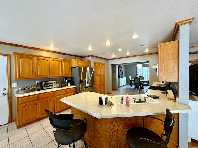 kitchen with light tile patterned floors, kitchen peninsula, stainless steel fridge, crown molding, and a breakfast bar area