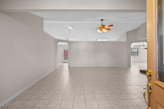 empty room with ceiling fan, vaulted ceiling, light tile patterned floors, and plenty of natural light