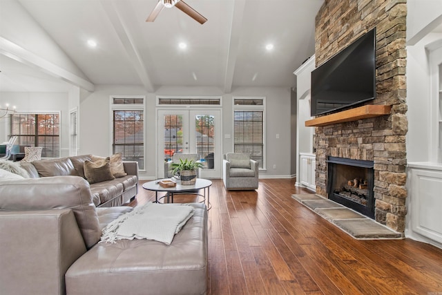 living room with ceiling fan, vaulted ceiling with beams, dark hardwood / wood-style floors, a stone fireplace, and french doors