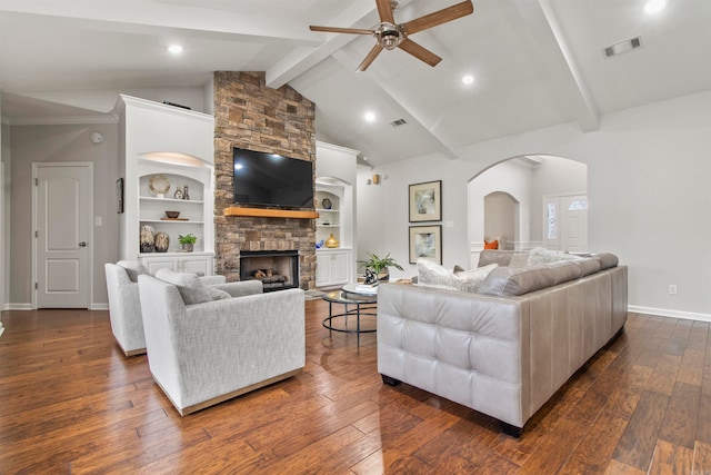 living room with beamed ceiling, dark wood-type flooring, a stone fireplace, and built in features