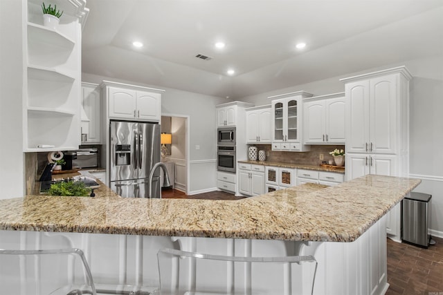 kitchen with appliances with stainless steel finishes, a kitchen bar, and white cabinets