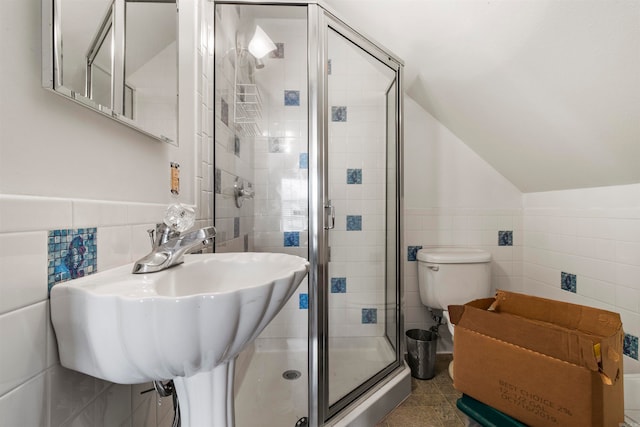 bathroom with lofted ceiling, toilet, sink, tile walls, and an enclosed shower