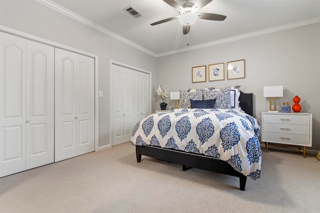 bedroom featuring crown molding, two closets, carpet flooring, and ceiling fan