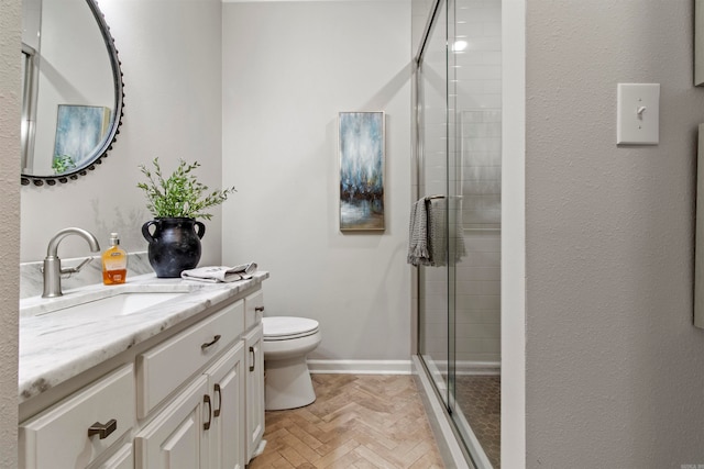 bathroom with vanity, walk in shower, toilet, and parquet flooring