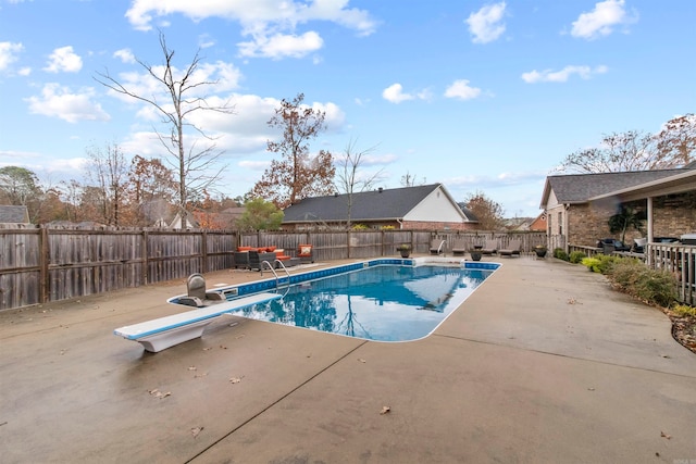 view of swimming pool with a patio and a diving board