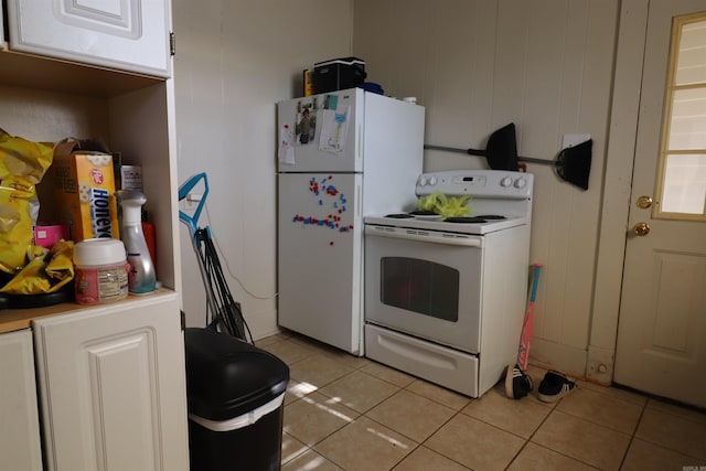 kitchen with white cabinets, white appliances, wooden walls, and light tile patterned floors