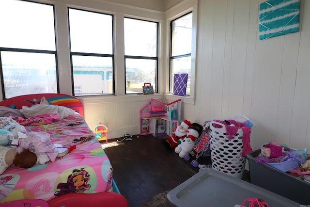 bedroom with hardwood / wood-style floors and wooden walls