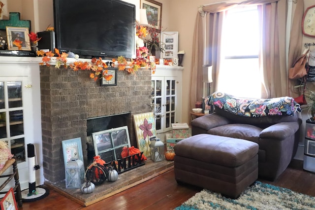 living room featuring a brick fireplace and dark hardwood / wood-style floors