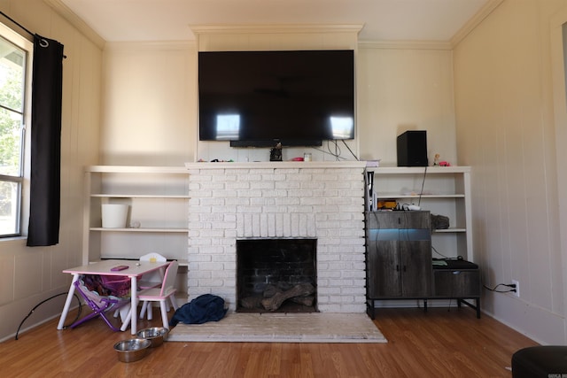 living room with a brick fireplace, wood-type flooring, and crown molding