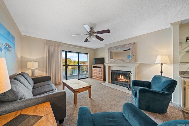 carpeted living room featuring crown molding, a textured ceiling, a tiled fireplace, and ceiling fan