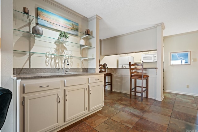 kitchen featuring white appliances, a textured ceiling, ornamental molding, and sink