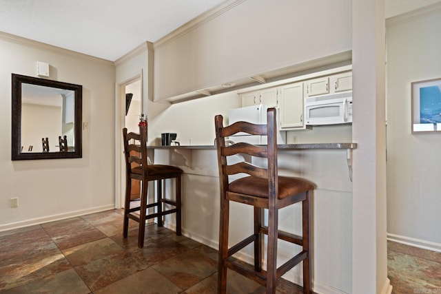 kitchen with white cabinets, crown molding, and a kitchen breakfast bar