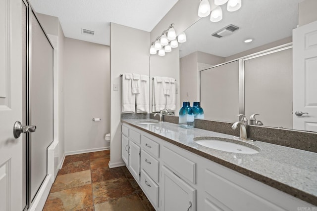 bathroom with vanity, a shower with shower door, a textured ceiling, and toilet