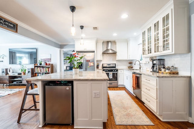 kitchen with wall chimney range hood, a center island, white cabinetry, and stainless steel appliances