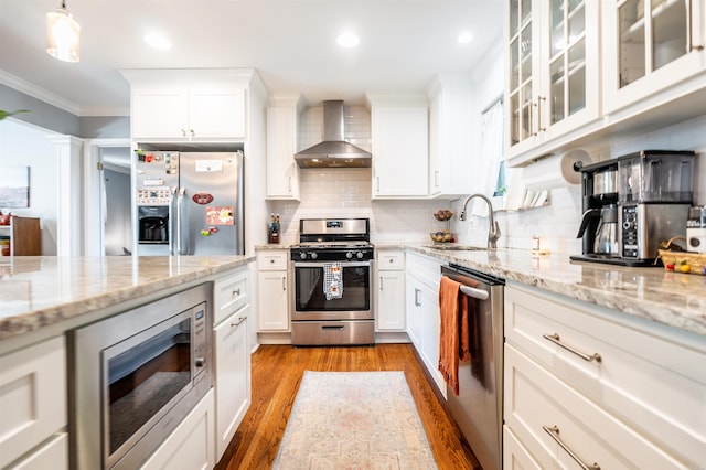 kitchen with white cabinetry, light hardwood / wood-style floors, wall chimney exhaust hood, and appliances with stainless steel finishes