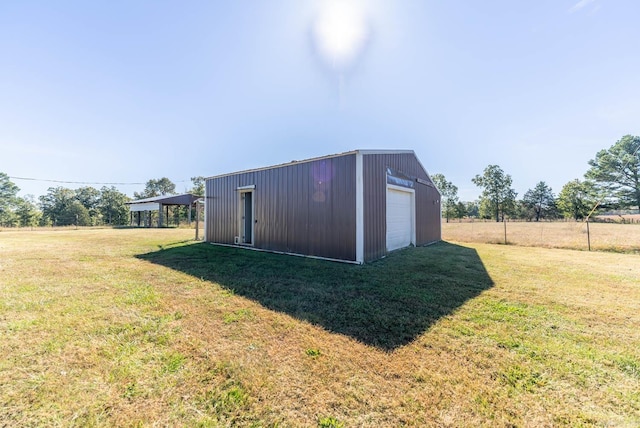 view of outdoor structure featuring a lawn, a rural view, and a garage