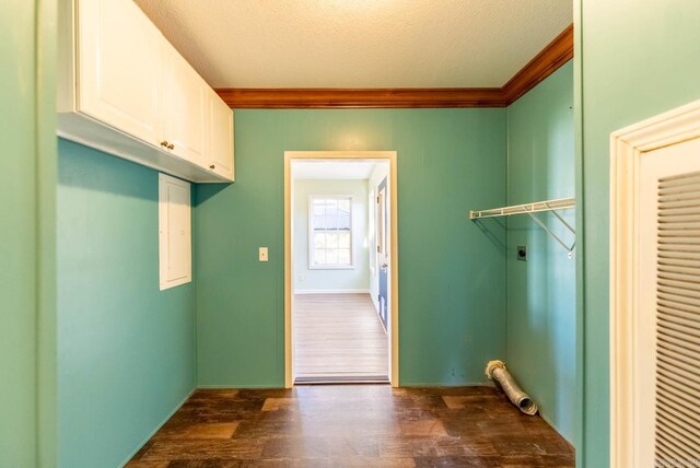 laundry area featuring electric dryer hookup, a textured ceiling, cabinets, and dark hardwood / wood-style floors