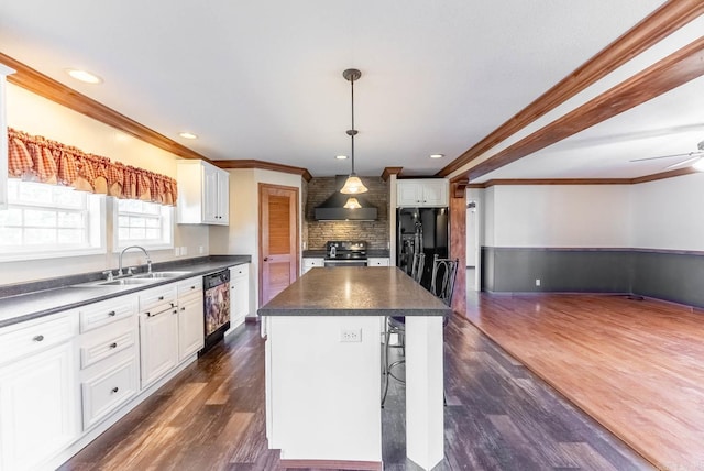 kitchen with white cabinets, a kitchen bar, black appliances, sink, and a center island