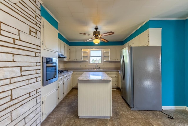 kitchen with ceiling fan, ornamental molding, stainless steel appliances, sink, and a center island