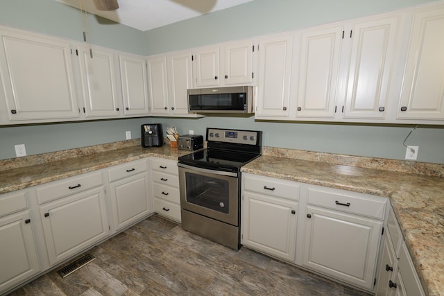 kitchen with appliances with stainless steel finishes, white cabinets, ceiling fan, and dark hardwood / wood-style floors