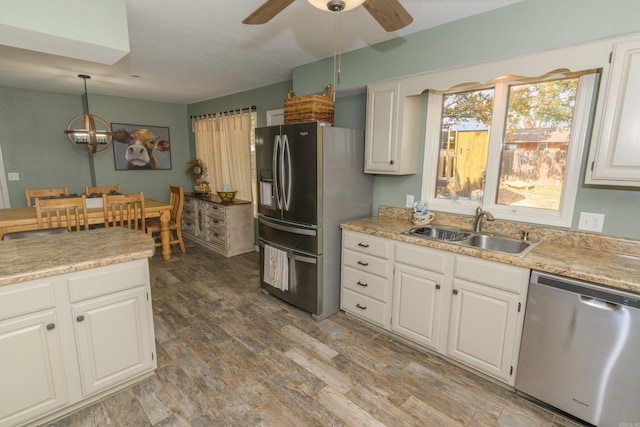 kitchen with white cabinets, hardwood / wood-style flooring, sink, decorative light fixtures, and stainless steel appliances