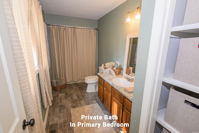 bathroom with toilet, curtained shower, hardwood / wood-style flooring, and vanity