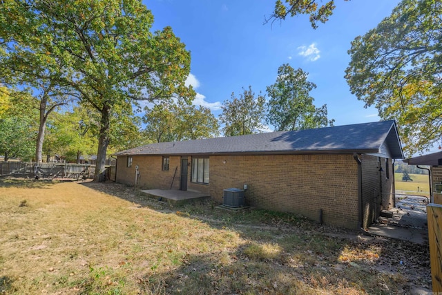 rear view of house featuring central AC and a yard