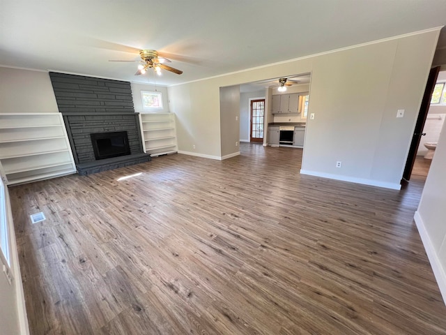 unfurnished living room with dark wood-type flooring, a stone fireplace, and plenty of natural light