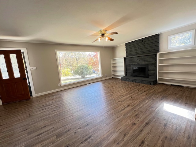 unfurnished living room featuring a wealth of natural light, a stone fireplace, and dark hardwood / wood-style flooring