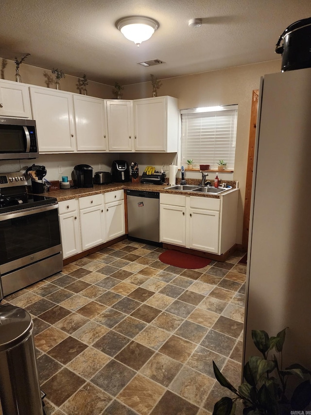 kitchen featuring white cabinetry, stainless steel appliances, a textured ceiling, and sink