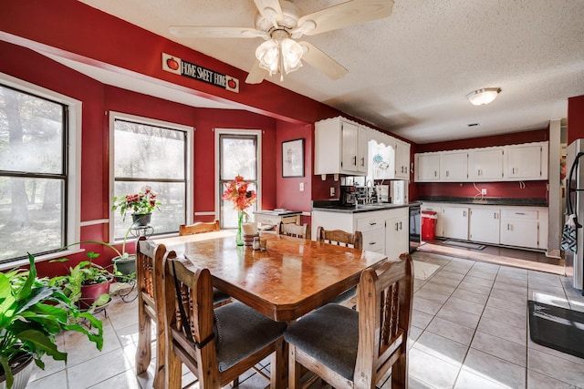 dining space featuring sink, ceiling fan, a textured ceiling, and light tile patterned floors