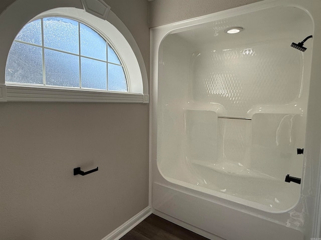 bathroom with hardwood / wood-style flooring and bathing tub / shower combination