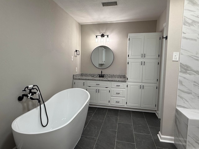 bathroom featuring vanity, a textured ceiling, tile patterned floors, and a bath