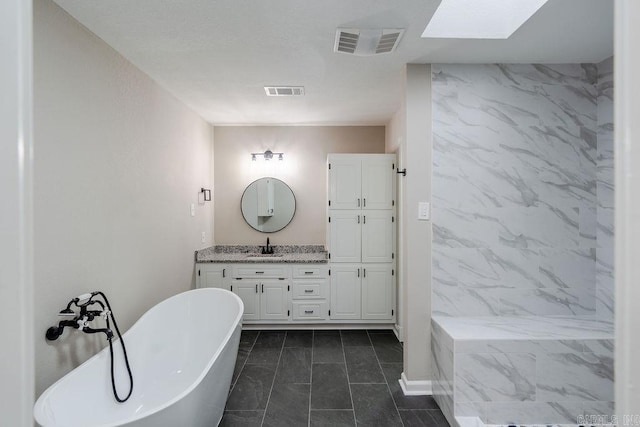 bathroom with vanity, a tub to relax in, a skylight, and tile patterned flooring