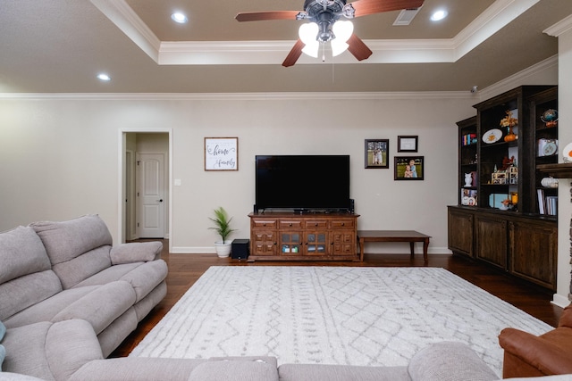 living room featuring ornamental molding, a raised ceiling, dark hardwood / wood-style floors, and ceiling fan