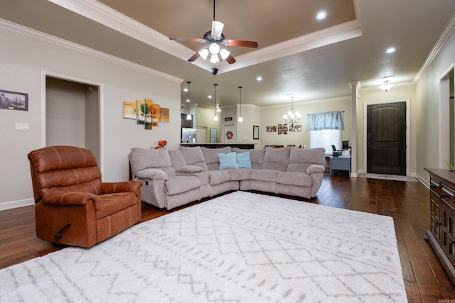 living room featuring dark wood-type flooring, crown molding, a raised ceiling, and ceiling fan with notable chandelier