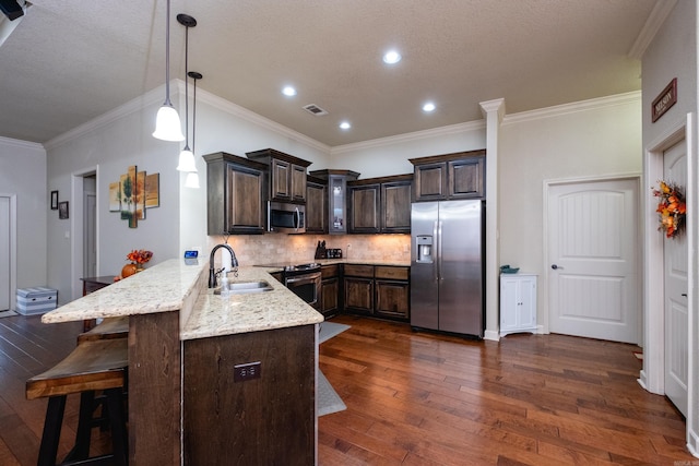 kitchen with appliances with stainless steel finishes, kitchen peninsula, and dark hardwood / wood-style floors