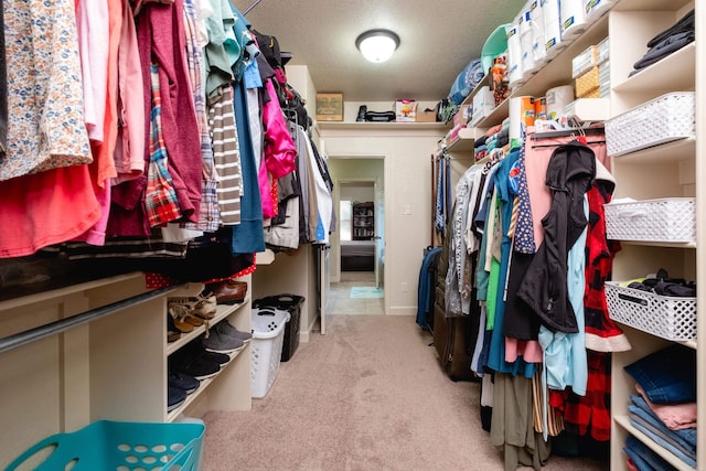 walk in closet featuring light colored carpet