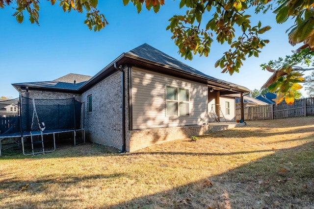 exterior space featuring a patio area, a lawn, and a trampoline