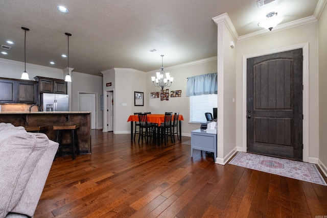 entryway featuring dark wood-type flooring, ornamental molding, a textured ceiling, and a chandelier