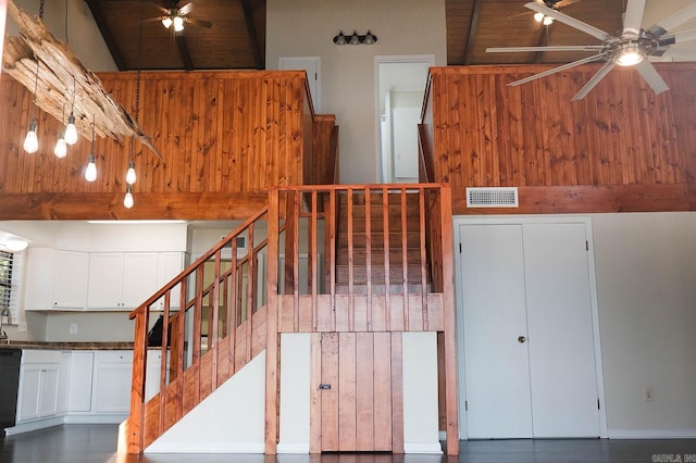 stairs featuring ceiling fan, a towering ceiling, beamed ceiling, and wooden ceiling