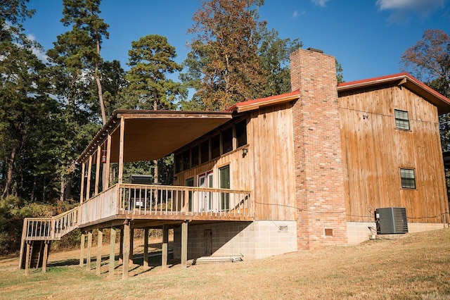 rear view of property with a wooden deck, cooling unit, and a lawn